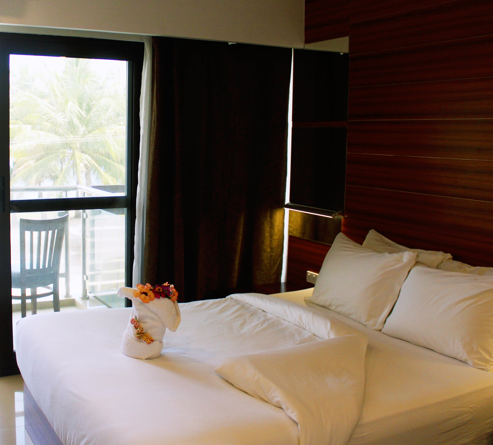 Guest room at Nambis Inn with balcony and palm trees outside